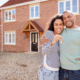 This is a couple looking happy, stood in front of a new house holding some keys because they followed the 5 Actionable Steps to Securing Their Dream Property in 2025